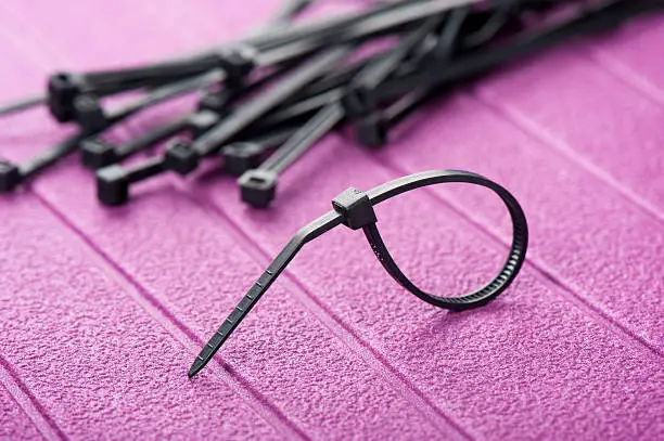 heap of black cable ties on purple background