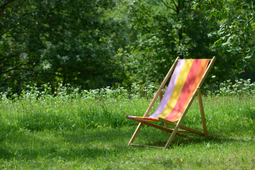 Wooden deckchair standing on the green in summer.