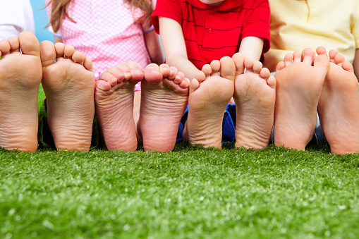 Happy friends sitting on the grass barefoot