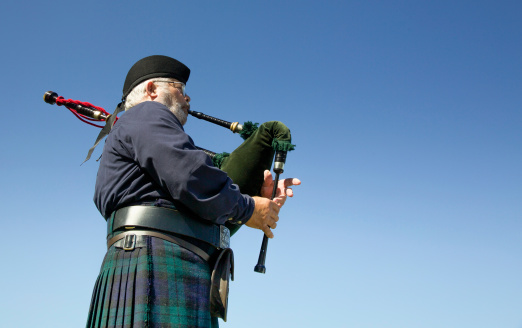 3rd July 2022: Scottish Game Fair. Rear view of a Highland Pipe Band playing at a traditional Scottish Game Fair in Perth. The pipe band have bagpipers and drummers. They are wearing traditional Highland dress, with kilts, sporrans and a traditional Scottish knife called a Sgian Dubh, tucked in their green wool socks.