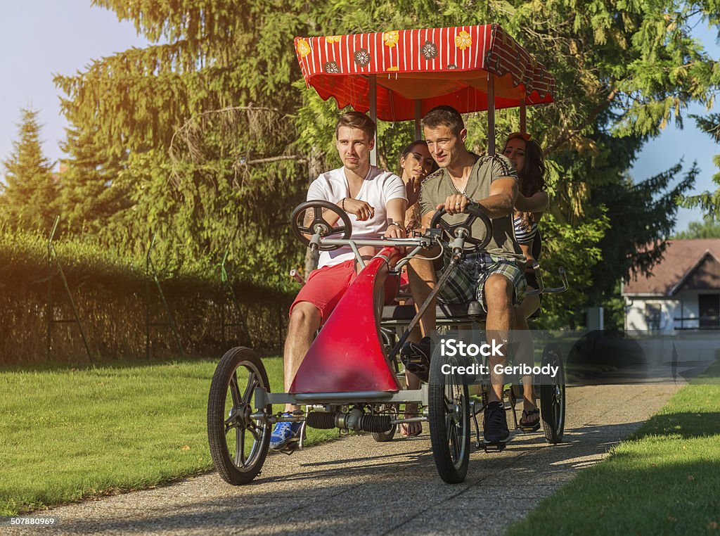 Four young people in a four-wheeled bicycle four young people in a four-wheeled bicycle Cycling Stock Photo