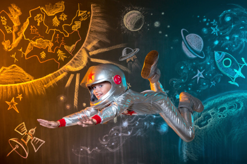 Cute girl astronaut floating in weightlessness at outer space. The illusion of flight on a background of the space drawing in chalk