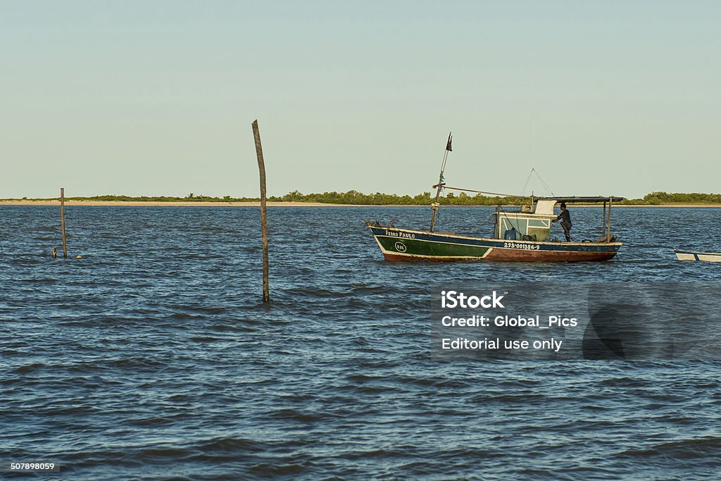 Fishing Boat Barra de Caravelas, Brazil - July, 02 2014: A young fisherman steering his small wooden hand made fishing boat and pulling another wooden canoe out of Caravela's Bay at Barra de Caravelas, Caravelas city, Bahia state - Brazil Canoe Stock Photo