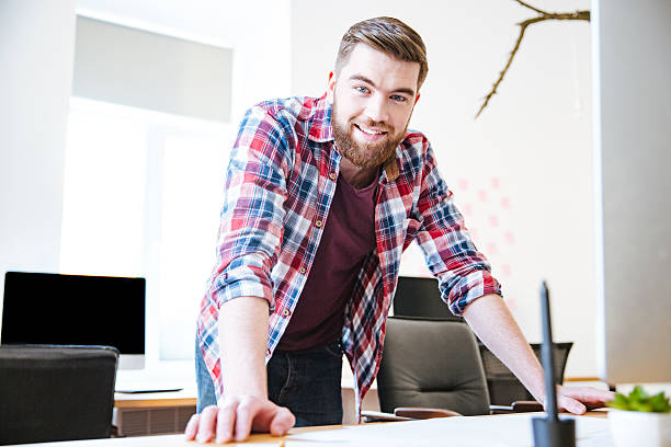 istock Smiling confident young male with beard standing in office 507901964