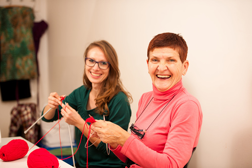 Women knitting with red wool. Eldery woman transfering knitting knowledge
