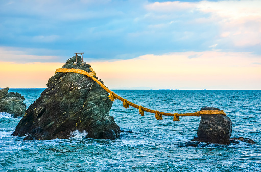 Meoto Iwa (夫婦岩?), or the Married Couple Rocks, are a couple of small rocky stacks in the sea off Futami, Mie, Japan. They are joined by a shimenawa (a heavy rope of rice straw) and are considered sacred by worshippers at the neighboring Futami Okitama