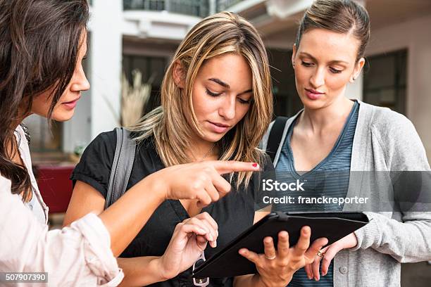 Group Of Friends Using A Tablet At The University Stock Photo - Download Image Now - 20-29 Years, Adolescence, Adult