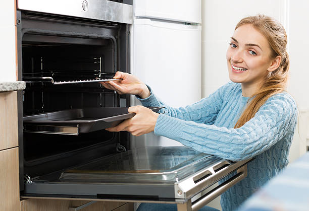 istock girl putting baking tray in kitchen oven 507907642