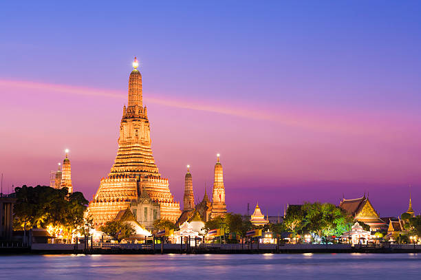 Wat Arun Temple at sunset in Bangkok, Thailand The illuminated temple of Wat Arun on the Chao Phraya river at sunset in Bangkok, Thailand bangkok stock pictures, royalty-free photos & images