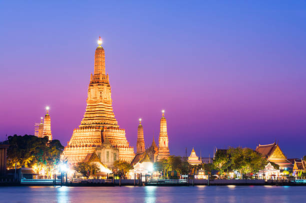 Temple of Wat Arun at sunset in Bangkok, Thailand The illuminated temple of Wat Arun on the Chao Phraya river at sunset in Bangkok, Thailand clear sky night sunset riverbank stock pictures, royalty-free photos & images