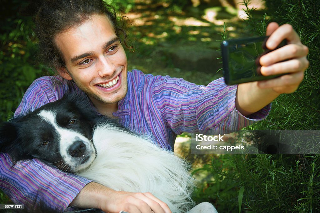 Selfie With The Dog.Color Image A 19 years old guy takes a selfie with his dog using a new generation smart phone. Adult Stock Photo
