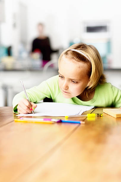 istock Little schoolgirl concentrating on her homework at kitchen table 507920079