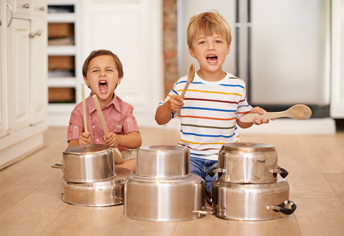 Two adorable young brothers using kitchen utensils as instruments
