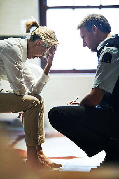 Homicide is a tragic business Shot of a grief stricken woman giving her statement to a police officer at a crime scene victims stock pictures, royalty-free photos & images