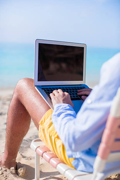 istock Young man working on laptop at tropical beach 507952611