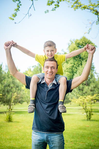 istock Cheerful man carrying his son on back against park 507954951