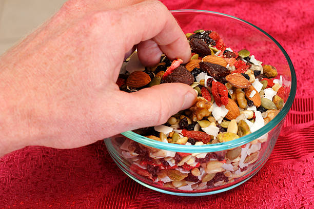 Gourmet Fruit and Nut Mix Healthy vegan trail mix of dry fruits and nuts of strawberry, blueberry, black currants, dates, pumpkin seeds, pine nuts, almonds, coconut, walnuts, pistachio, raisins, sesame seeds, and pine nuts.. nut variation healthy lifestyle pistachio stock pictures, royalty-free photos & images