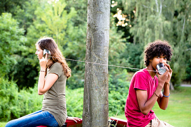 jeune couple multi-ethnique de communiquer grâce à un téléphone en boîte de conserve - tin can phone photos et images de collection