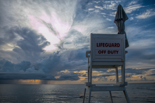 An empty lifeguard post on an early morning with impending storm in the distance
