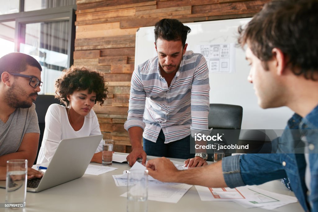 Joven hablando de investigación de mercado con sus colegas - Foto de stock de Oficina de empleo libre de derechos