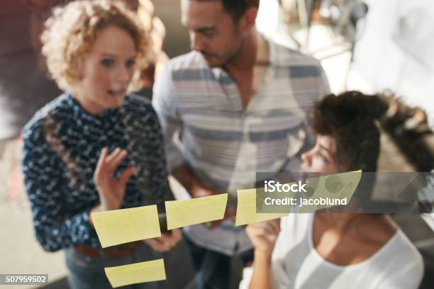 Three Business People Having A Meeting At Sticky Note Wall Stock Photo - Download Image Now