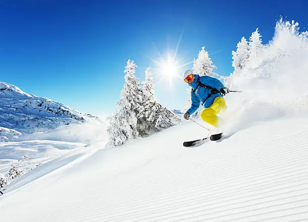 Man skier running downhill on sunny Alps slope