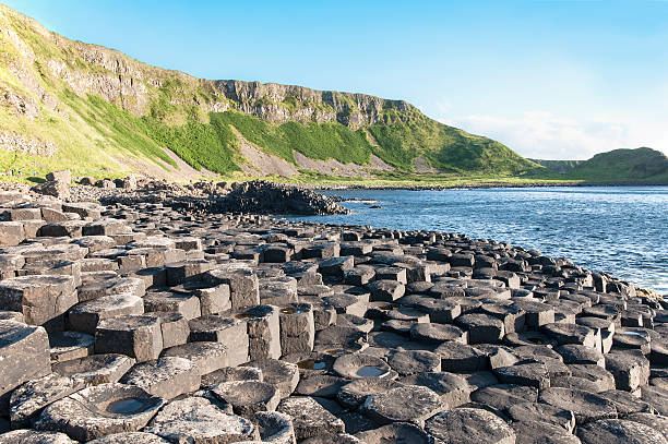 Giants Causeway and cliffs in Northern Ireland Giants Causeway, unique geological formation of hexagonal volcanic basalt rocks and cliffs in Antrim County, Northern Ireland, in sunset light giants causeway photos stock pictures, royalty-free photos & images