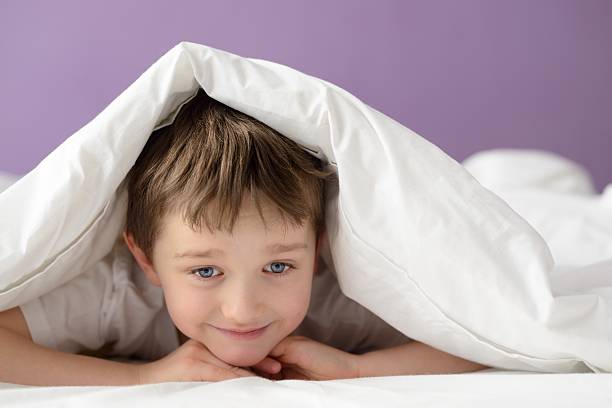 istock boy playing in bed under a white blanket or coverlet 507972014