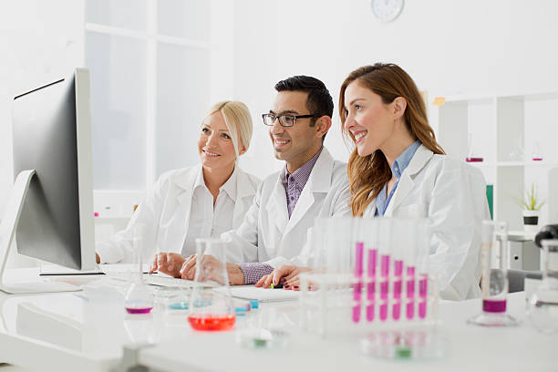 Multi-Ethnic group of scientists working in a lab. Confident multi-ethnic group of scientists at work in a lab. Sitting and discussing in front of monitor. chemical worker stock pictures, royalty-free photos & images