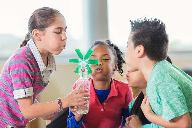 Elementary students studying alternative wind energy in science class Elementary age diverse little boys and little girls are studying alternative energy using homemade windmills during public school science class. African American, Caucasian, and Hispanic students are working on project together during class. school science project stock pictures, royalty-free photos & images