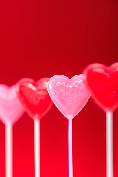 istock Row of heart shaped lollipops on red background 508002758