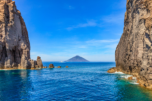 The island of Stromboli seen among the rocks off the island of Panarea. Aeolian archipelago, Sicily, Italy.
