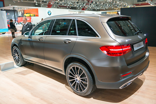 Brussels, Belgium - Januari 12, 2016: Mercedes-Benz GLC-Class is a small luxury SUV rear view. This GLC 220 d 4MATIC is fitted with a diesel engine and an automatic transmission. The car is on display during the 2016 Brussels Motor Show. The car is displayed on a motor show stand, with lights reflecting off of the body. There are people looking around and other cars on display in the background.