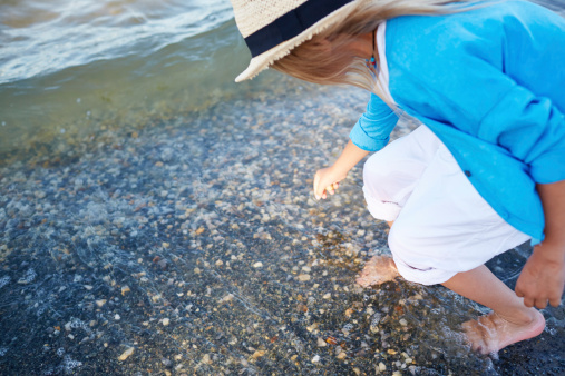 Little girl collecting sea pebbles