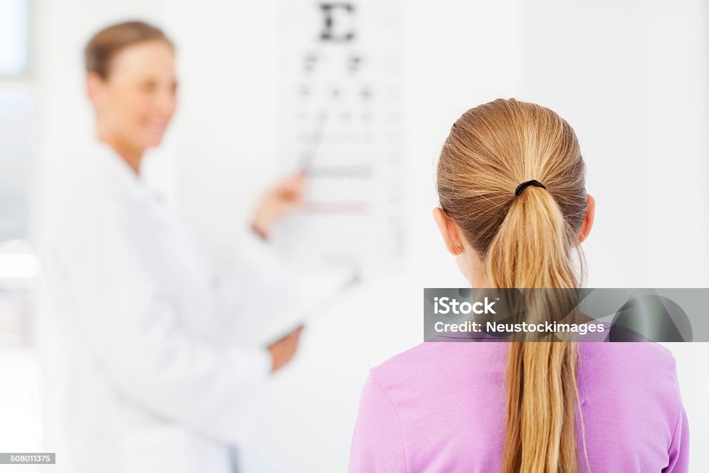 Menina lendo tabela ao pediatra escritório - Foto de stock de Exame de Vista - Exame Médico royalty-free