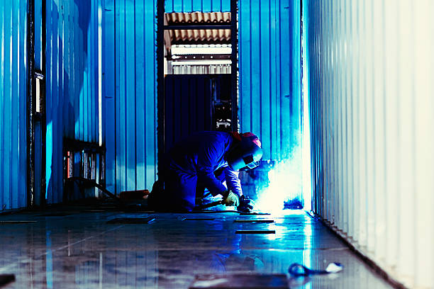 istock Blue-toned image of steelworker busy welding inside cargo container 508011807