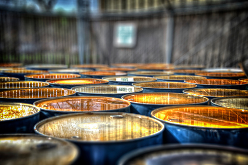 A group of oil drums with rain water on the tops showing a reflection of a sign that reads \