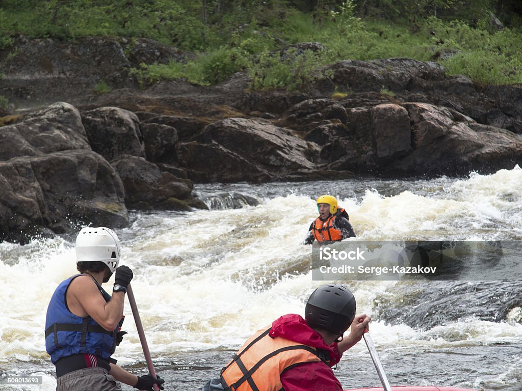 Two rowers on the catamaran trying to save Two rowers on the catamaran trying to save a drowning man in the river with rapids Rescue Stock Photo