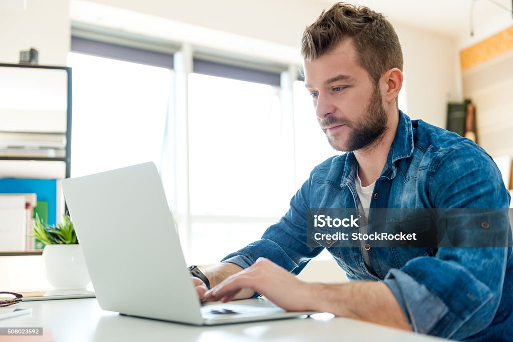 Young man working on laptop Young hipster working in his office Adult Stock Photo