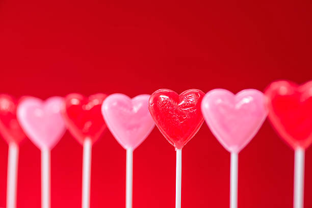 istock Row of heart shaped lollipops on red background 508023868