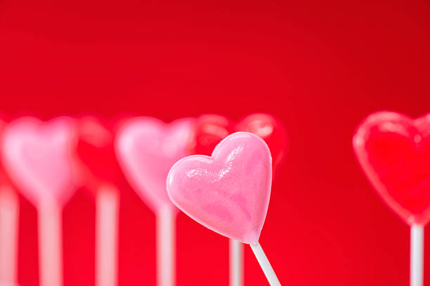 istock Row of heart shaped lollipops on red background 508024694