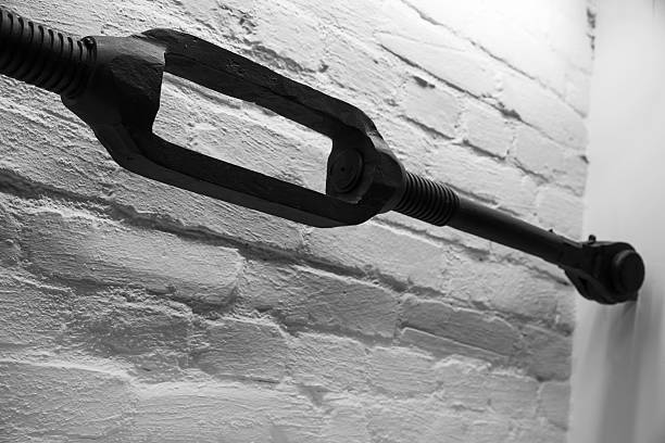 istock Old black turnbuckle, closeup photo over white brick wall 508025954