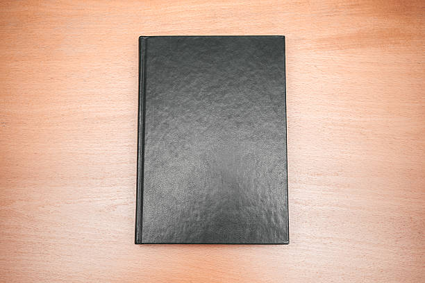 istock Book with empty black cover laying on wooden table 508026120