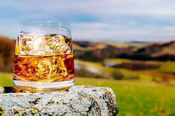 Glass of whisky on the rocks, literally and metaphorically, outdoors in the Scottish Highlands AdobeRGB colorspace.