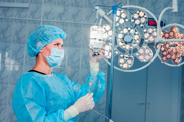 infirmière ajustant perfusion bouteille avec contre-plan de l'o - iv drip chemotherapy drug bag intensive care unit photos et images de collection