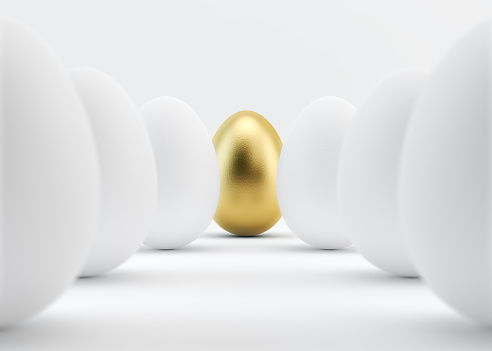 A golden egg is standing out from white eggs. The eggs are in two rows. Golden egg is in the middle. Isolated on white background. Clipping path is included.