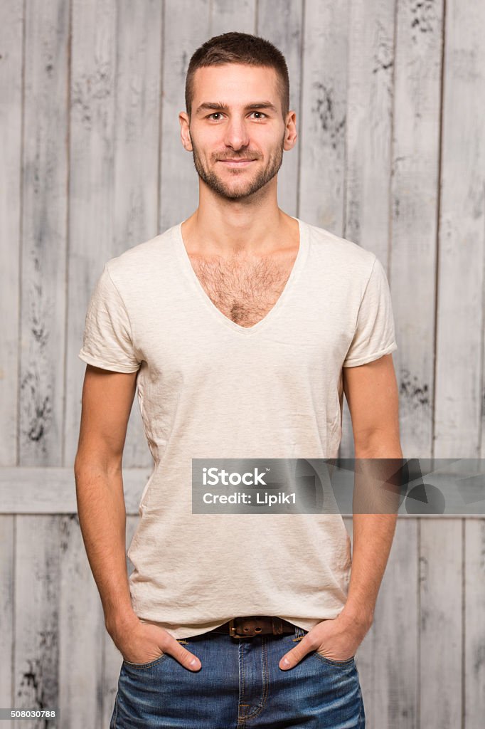 Model man posing Portrait of handsome man posing for photographer while keeping hands in pockets and smiling fot the camera in studio. Adult Stock Photo
