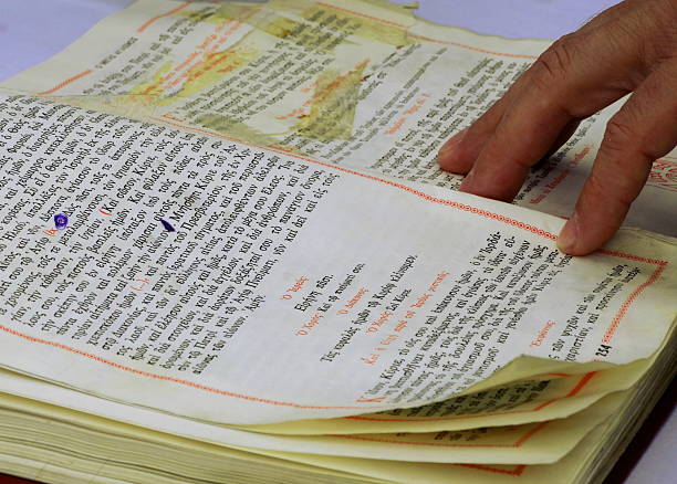 Priest's Hand On Greek Bible Priest's hand following lines in an old Greek Bible greek orthodox stock pictures, royalty-free photos & images