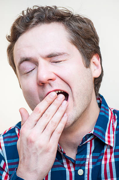 istock Young, tired, yawning, curly man covers his open mouth 508035022