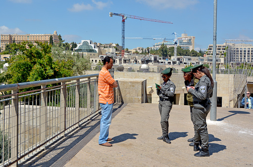 Jerusalem, Israel - May 4 2015: Israeli border patrol policewomen check an Arab man's ID and work permits. The force securing Israel borders and assisting IDF and law enforcements in the West Bank and Jerusalem.